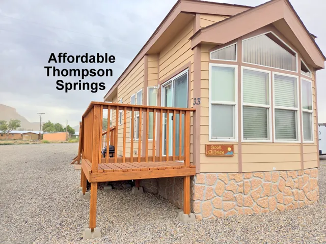 Exterior featuring light-colored siding, a wooden deck, and a stone-look foundation