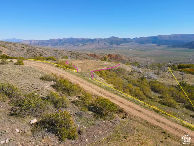 Expansive hillside property with a dirt road, offering a vast mountain and valley backdrop