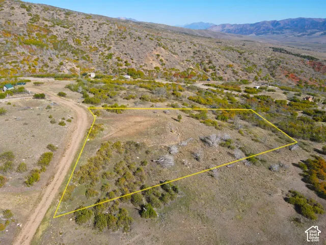 Expansive lot featuring a dirt road, varied terrain, and surrounding mountainous landscape