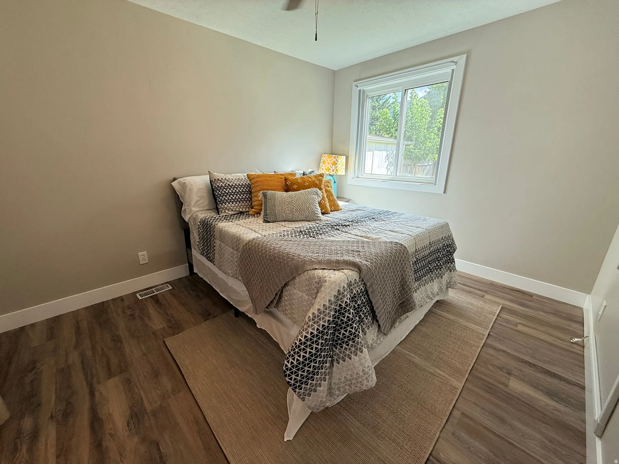 Wood-finish flooring, neutral wall tones, white trim, and a window with white casing