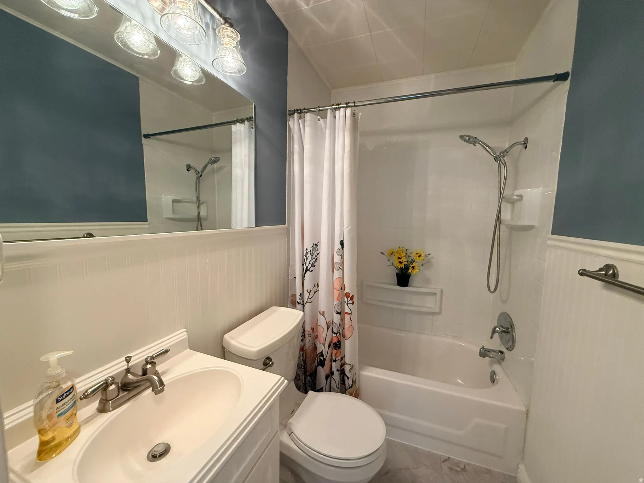 White vanity with an integrated sink and brushed nickel faucet, a white toilet, and a white bathtub with a shower fixture