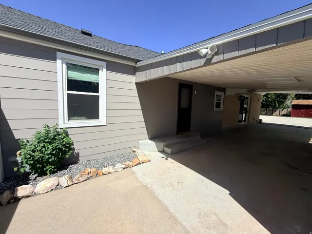 Carport entry with a concrete surface, gray siding, and a gabled roof