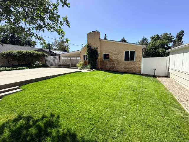 Expansive lawn area with a concrete driveway and a covered carport