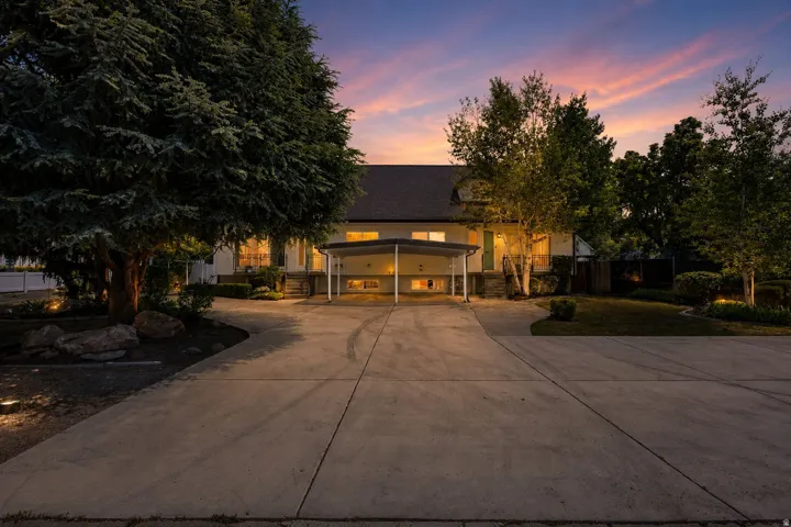 Two-story residence featuring a covered carport, concrete driveway, and mature landscaping