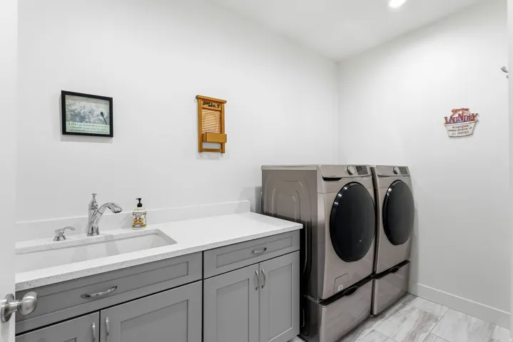 Laundry area featuring a utility sink, light gray cabinetry, white countertops, and wood-finish tile flooring