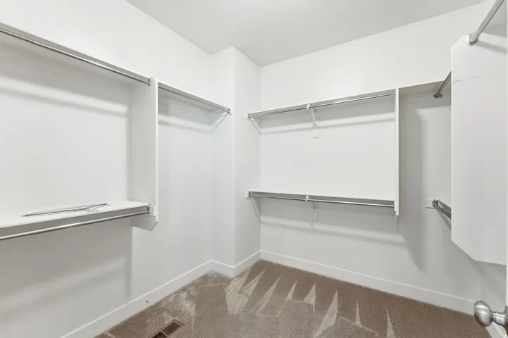 Walk-in closet featuring extensive built-in shelving and multiple hanging rods