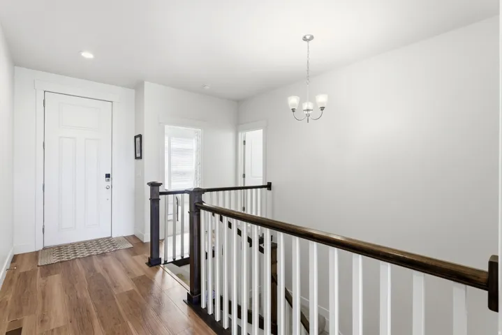 Entryway featuring wood-finish flooring, white paneled door, and recessed lighting