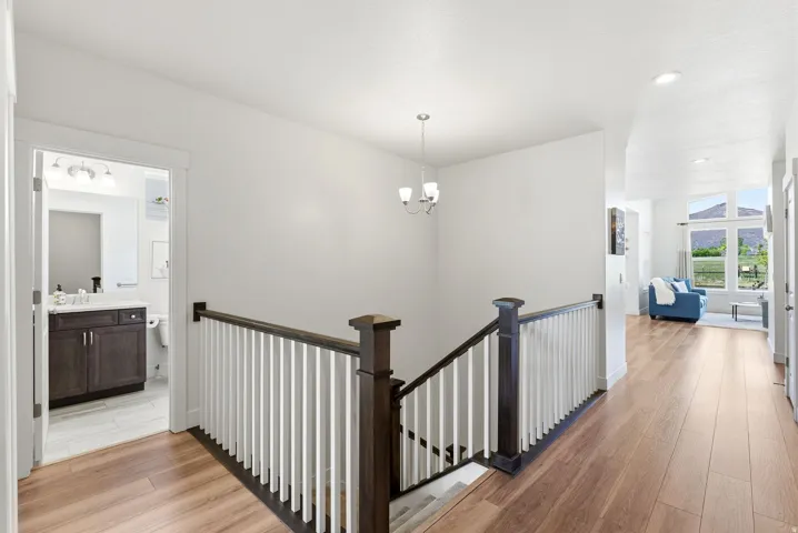 Hallway with wood-finish flooring, white walls, and a dark wood and white baluster staircase
