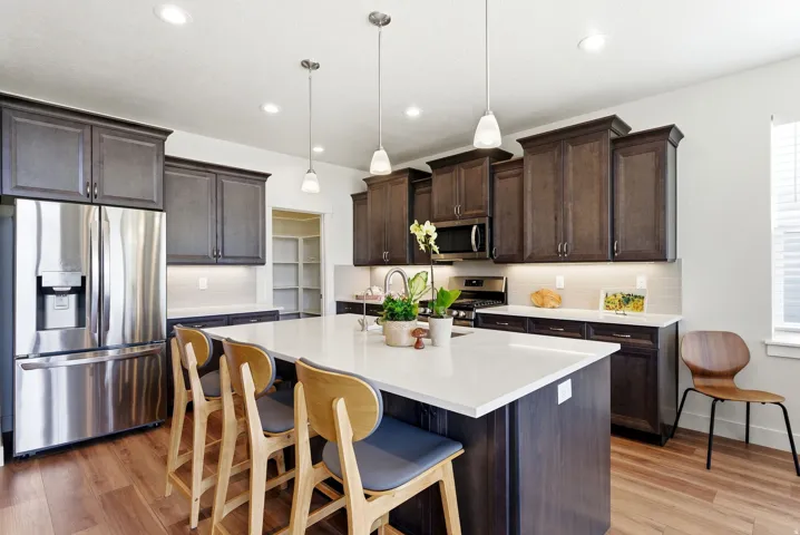 Kitchen featuring a central island with countertop seating, dark wood-finish cabinetry, stainless steel appliances, and wood-finish flooring