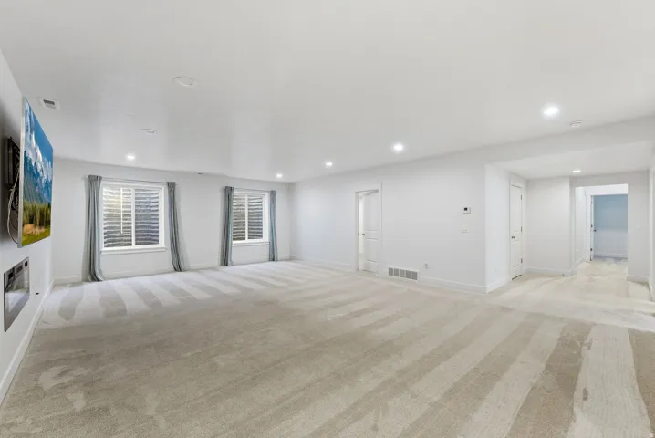 Spacious room featuring light-colored carpeting, recessed lighting, and white walls