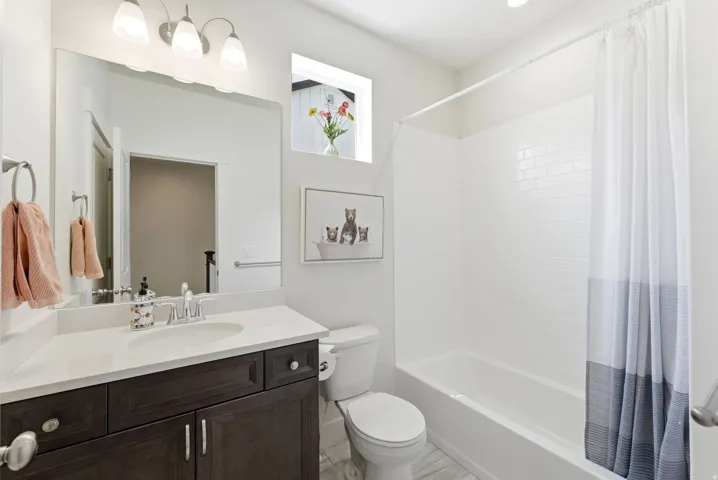 Bathroom featuring a dark wood-finish vanity with a light countertop, an integrated sink, and a chrome faucet