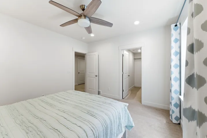 Carpeted room with a ceiling fan featuring wood-finish blades and a central light fixture