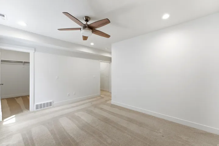 Spacious room featuring neutral carpeting, a ceiling fan with integrated lighting, and recessed ceiling lights