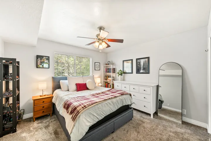Bedroom featuring carpet flooring, a ceiling fan with integrated lighting, and a large window