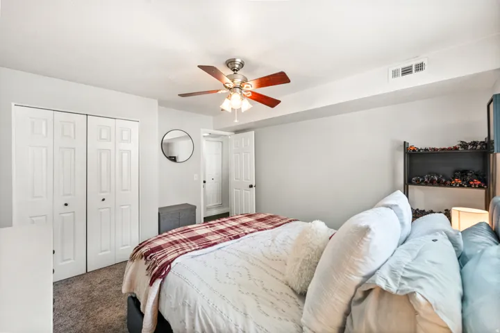 Recessed bedroom featuring neutral wall tones, carpeted flooring, a ceiling fan with light fixture, and bi-fold closet doors