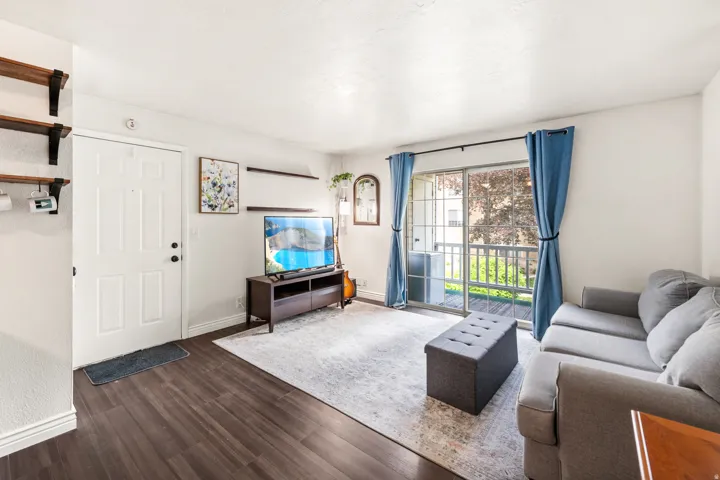 Living area featuring wood-finish flooring, white baseboards, and a sliding glass door to a private balcony