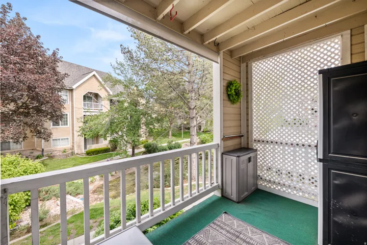 Private balcony featuring a white railing, lattice privacy screen, and green outdoor carpeting