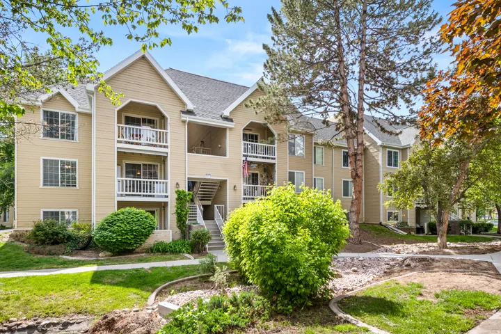 Multi-level condominium building featuring a light-toned exterior with multiple balconies and exterior staircases
