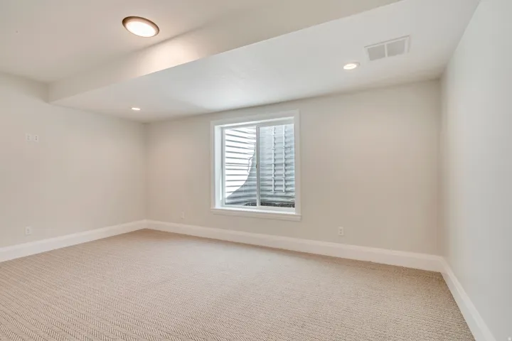 Finished room with a window well, recessed lighting, and a textured beige carpet