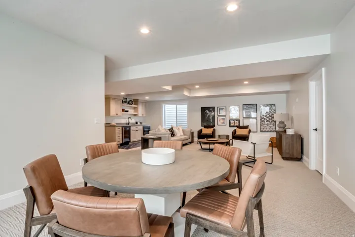Spacious multi-functional room featuring a wet bar with light wood cabinetry, a stainless steel sink, and dark lower appliances