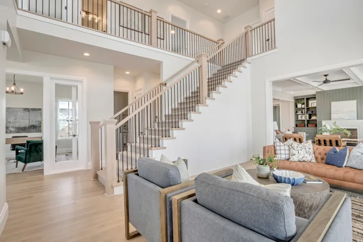 Bright, open living space featuring a two-story entryway with a light wood-finish staircase and black metal balusters