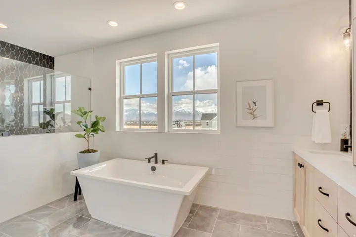 Freestanding soaking tub with matte black fixtures, set against a backdrop of two double-hung windows
