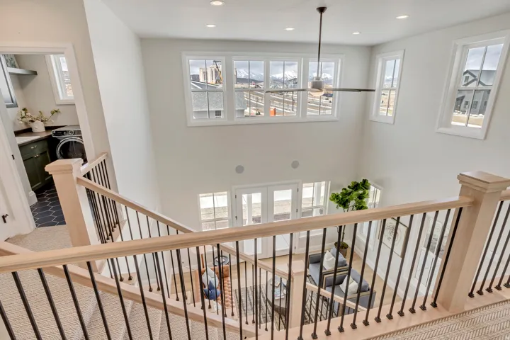 Two-story entry featuring light wood stair railings with black balusters and a carpeted staircase