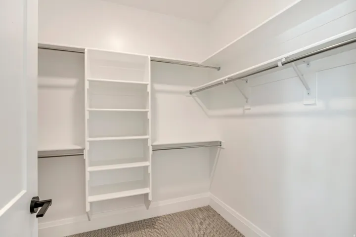 Custom closet organization system featuring white shelving and chrome hanging rods