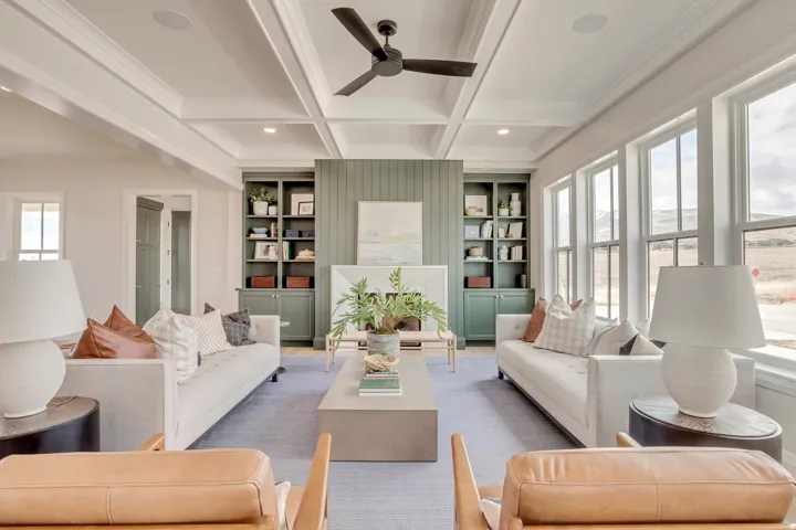 Bright living space featuring a coffered ceiling with a ceiling fan, a fireplace with built-in shelving, and large windows