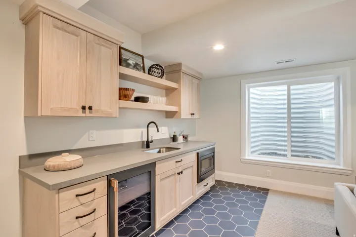 Wet bar featuring light wood cabinetry, stone countertops, a matte black faucet, integrated beverage refrigerator, and a built-in microwave
