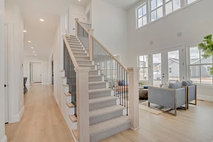 Two-story living area featuring a grand staircase with carpeted treads and an open baluster design