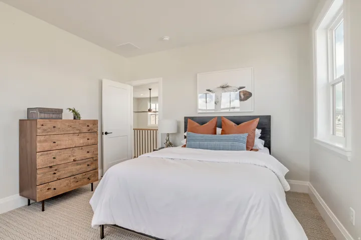 Carpeted bedroom with a single window, white trim, and a white interior door with dark hardware