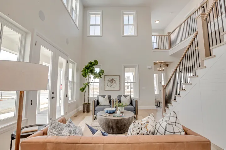 Two-story living area featuring abundant natural light, hardwood flooring, a staircase with metal balusters, shiplap detailing, and a second-story landing with an open railing