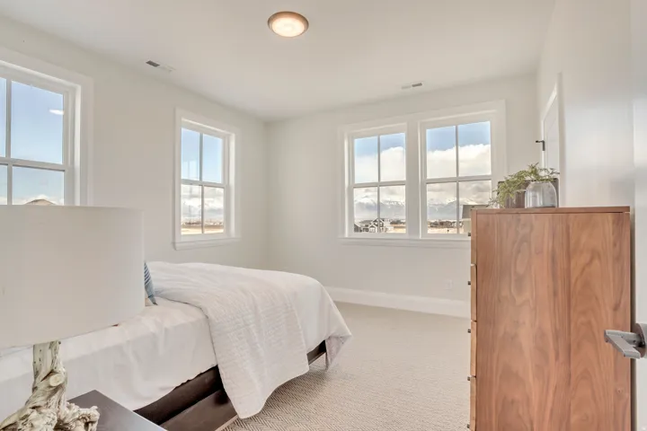Bright room featuring four windows with white frames, carpet flooring, a flush-mount ceiling light, and white walls