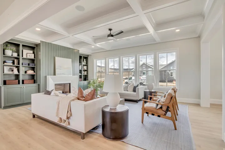 Spacious living area featuring light wood-finish flooring, a coffered ceiling with recessed lighting, and a modern ceiling fan