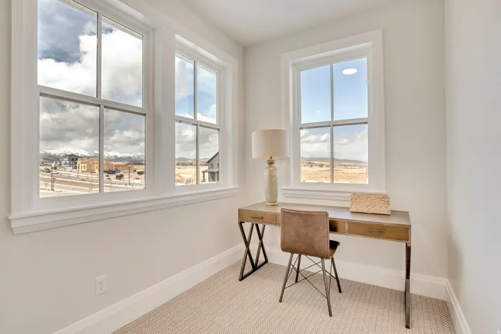 Bright room featuring multiple windows with grid patterns, offering expansive scenic views of distant mountains and surrounding properties