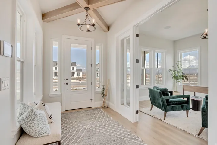Entryway featuring a vaulted ceiling with exposed wood beams, a glass-paneled front door, and sidelight windows