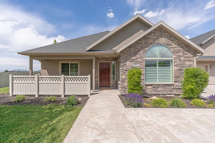 Stone veneer exterior with an arched window, covered entryway, and a solid wood front door