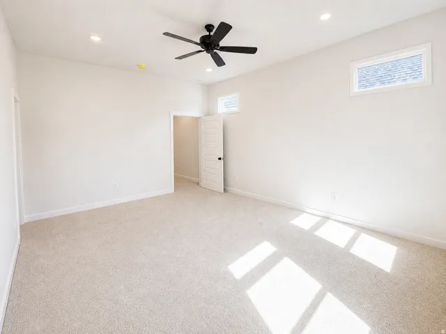 Spacious room featuring neutral carpet flooring, recessed lighting, and a modern black ceiling fan