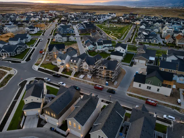 Expansive aerial of a modern residential development featuring numerous single-family homes with varied architectural styles and dark-shingled roofs