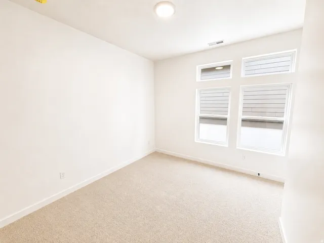 Room featuring a light-colored carpet, white walls, and white baseboards