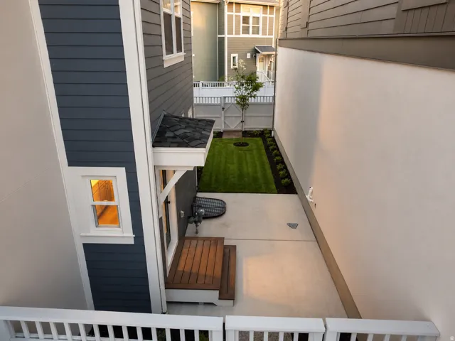 Outdoor patio featuring concrete surfacing, a wooden deck, and a manicured lawn area