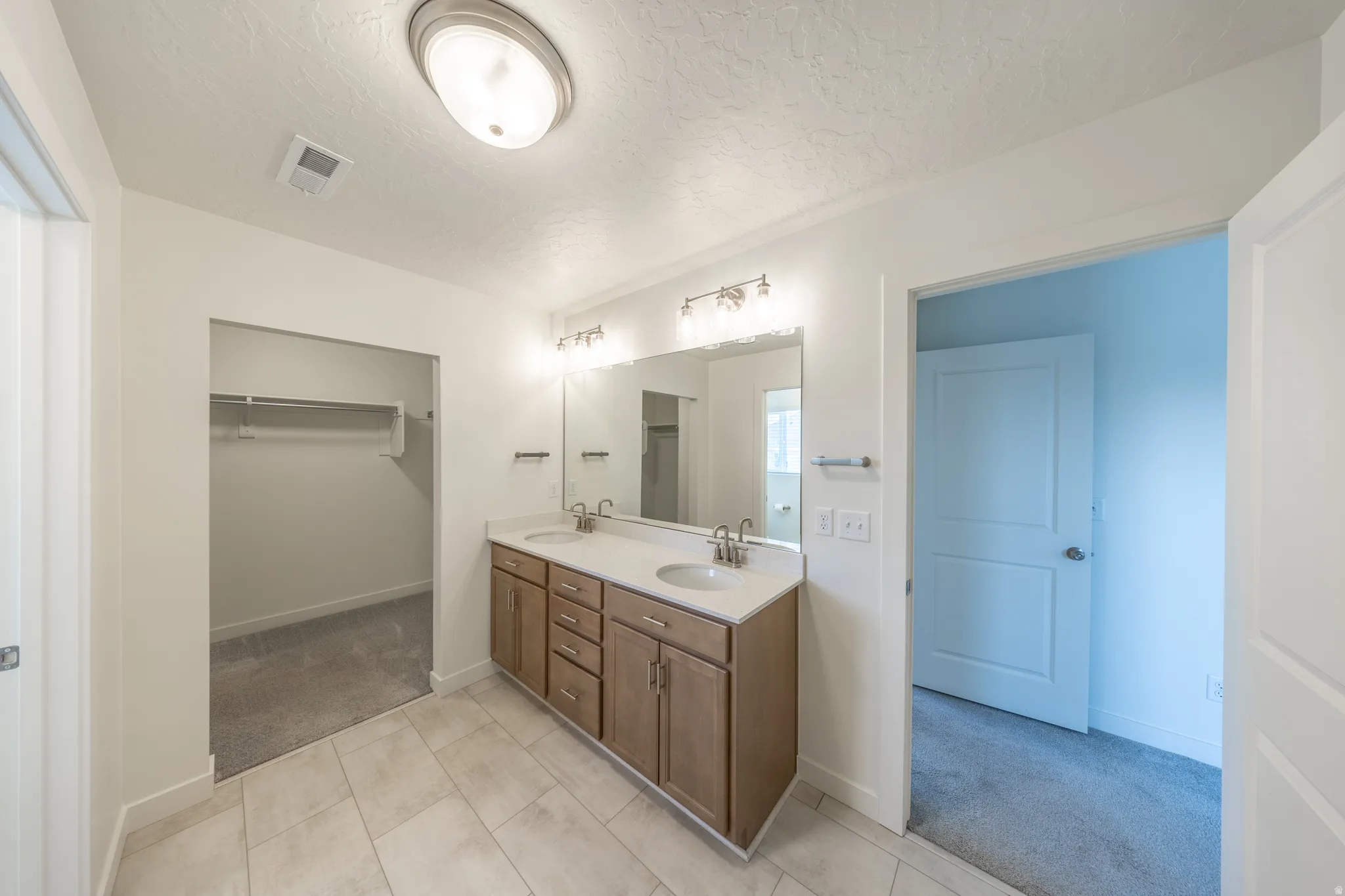 Primary bathroom featuring double sinks and walk in closet