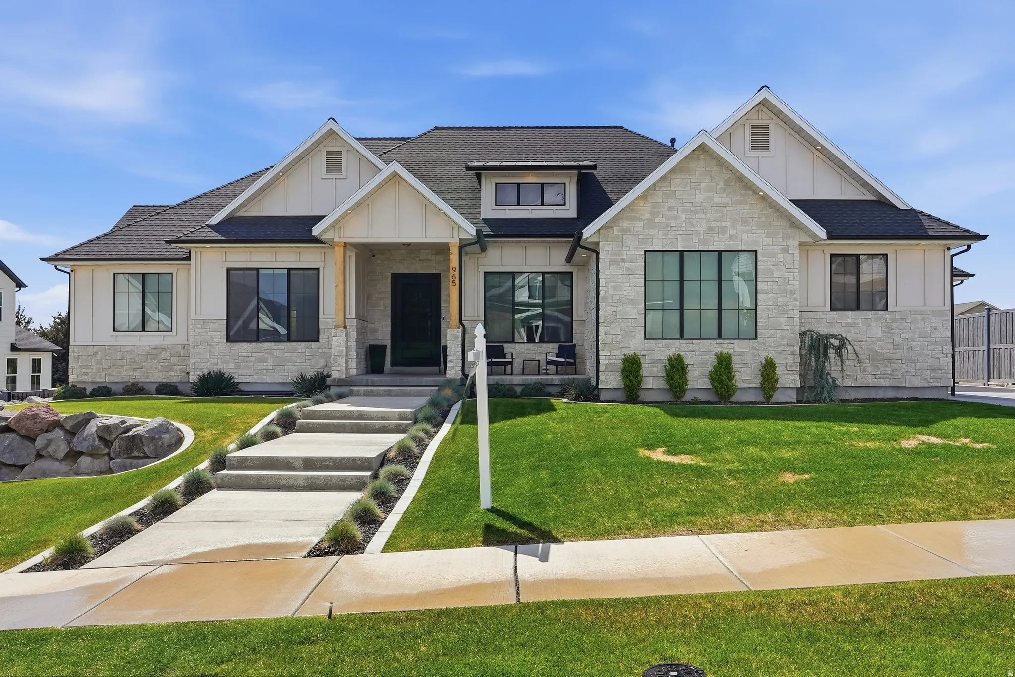 Modern farmhouse exterior featuring board and batten siding, stone facade, and a dark shingle roof
