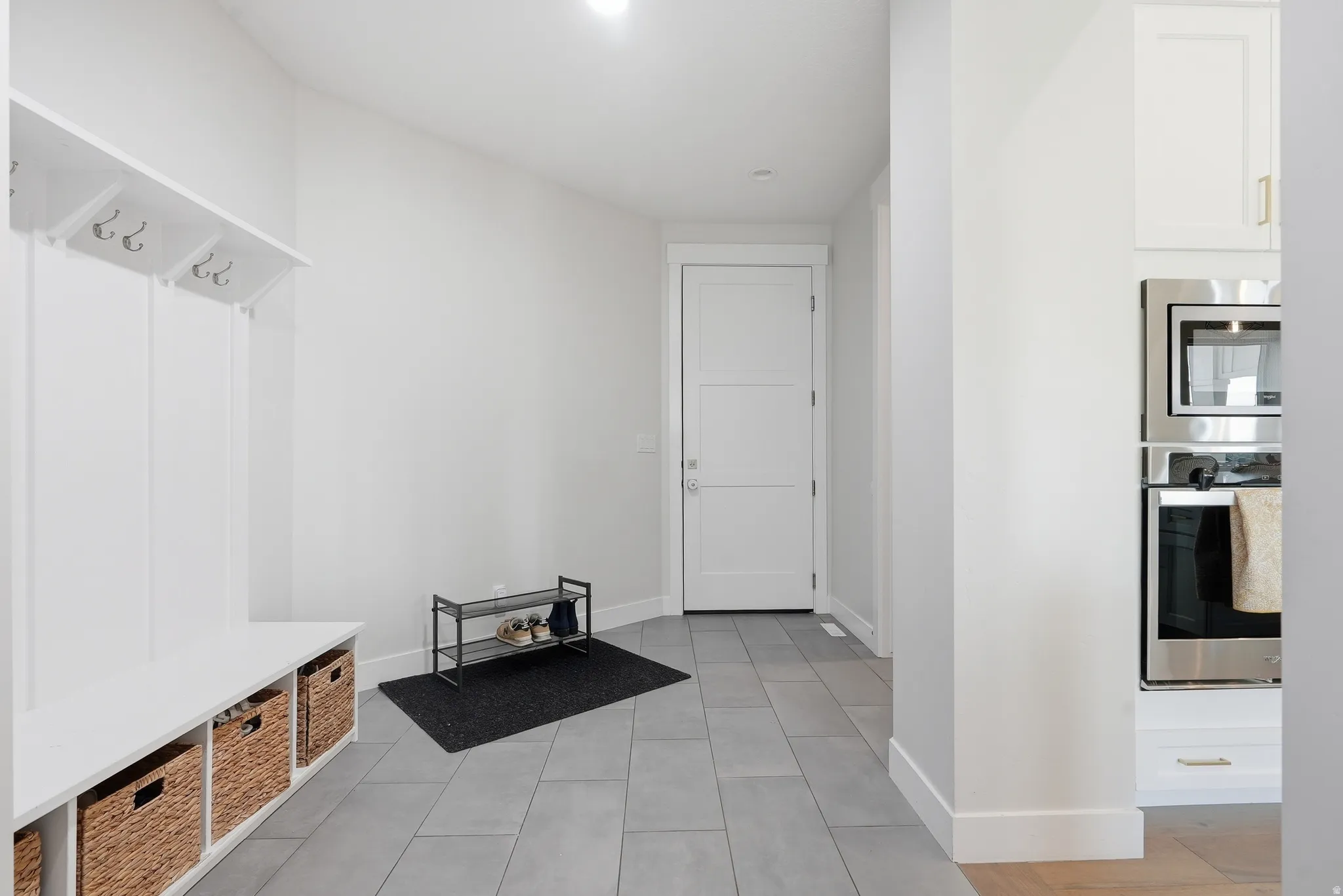 Entryway featuring tile flooring, white built-in bench with storage, integrated coat hooks, and a white paneled door