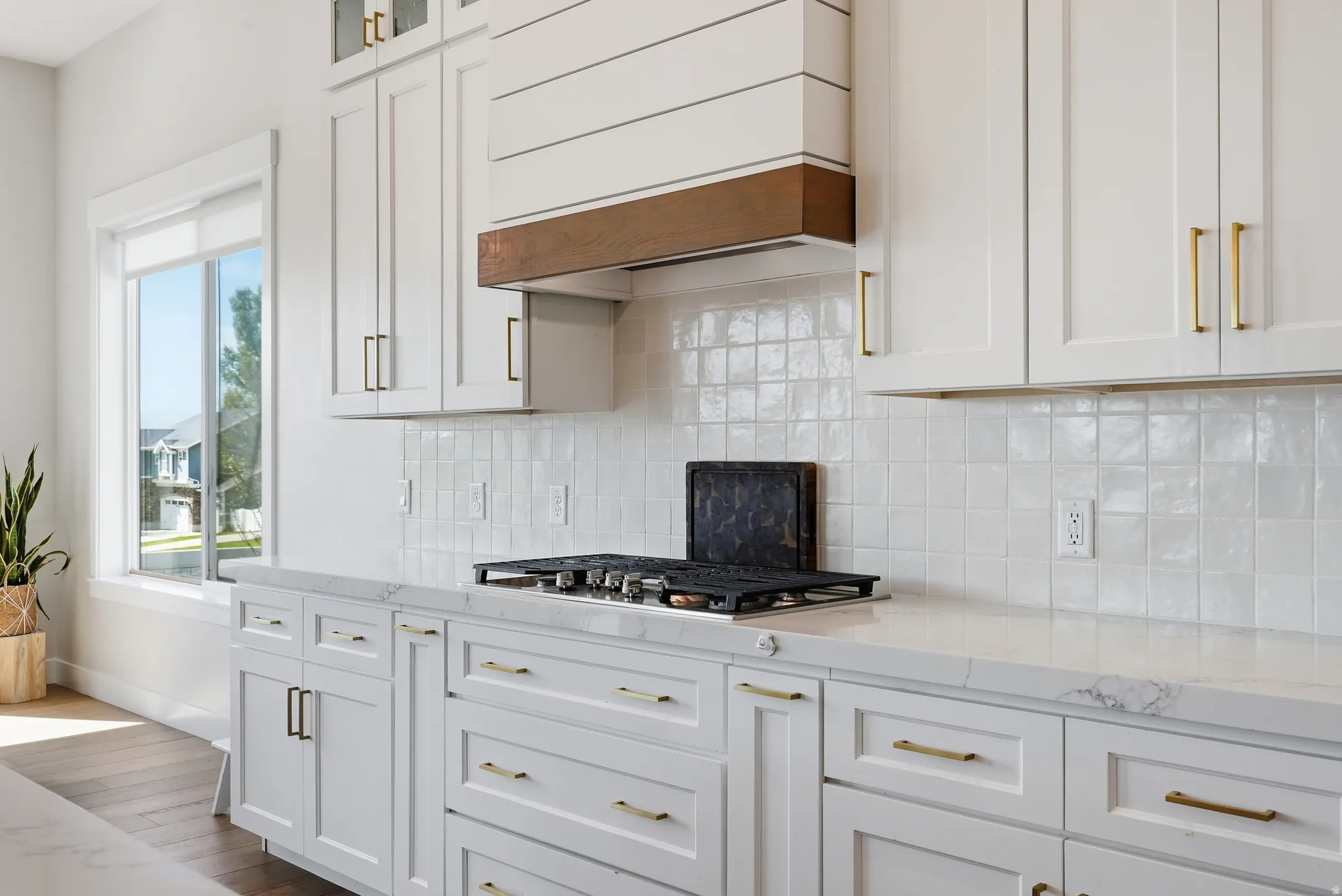 Modern kitchen featuring white shaker cabinetry, gold-tone hardware, a white subway tile backsplash, and light-toned countertops