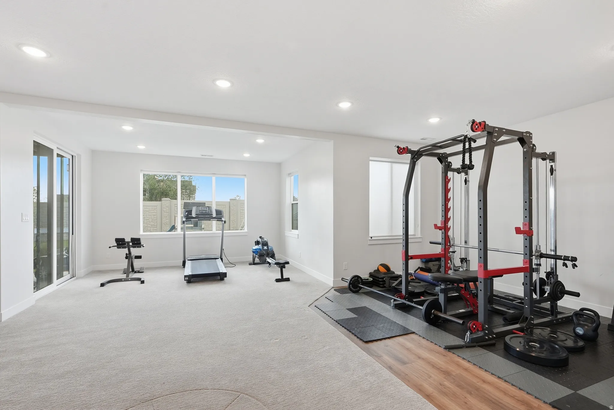 Spacious multi-purpose room featuring light-colored carpet, recessed lighting, and ample natural light from multiple windows and a glass slider