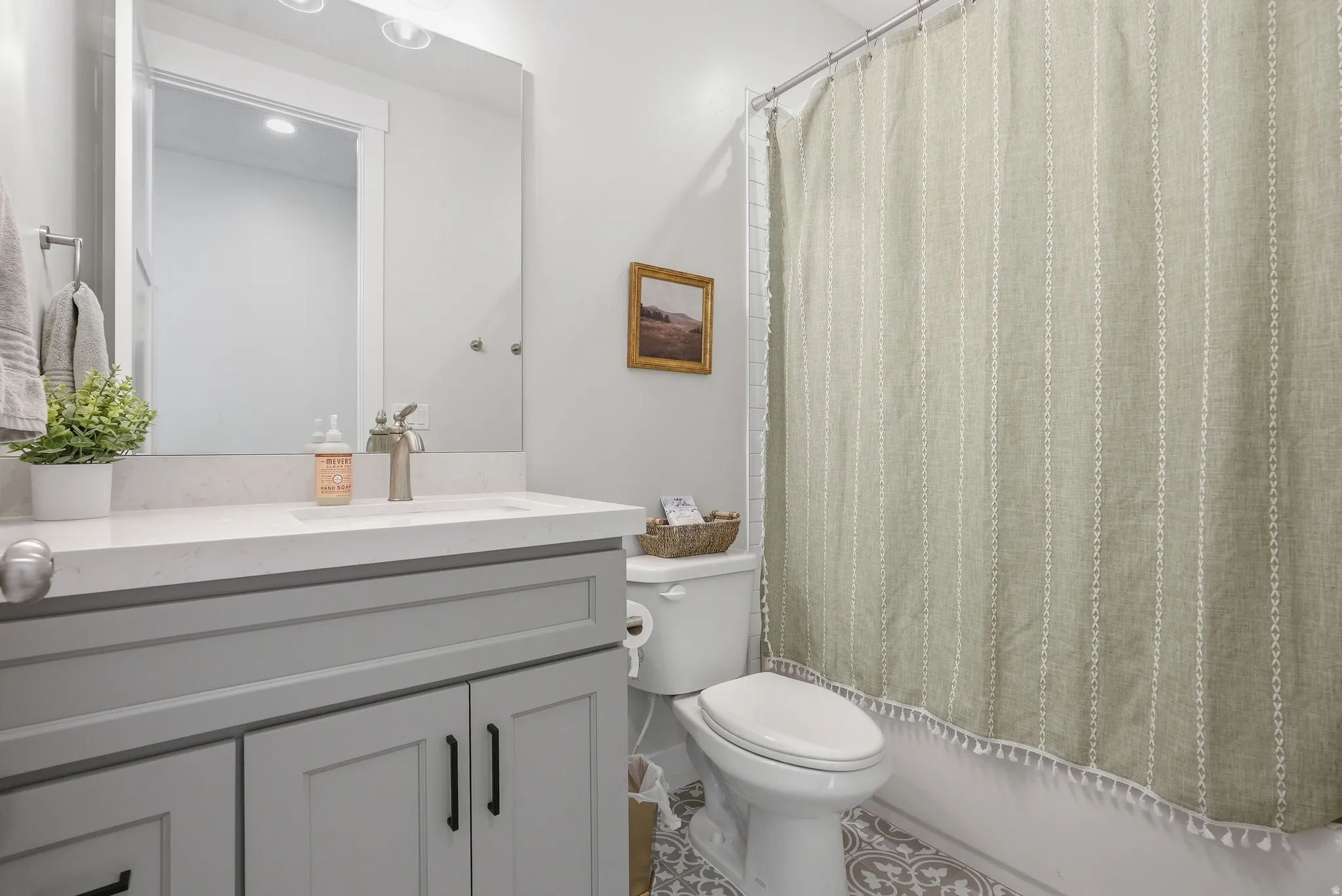 Bathroom vanity featuring a light gray shaker cabinet, white countertop, and brushed nickel faucet