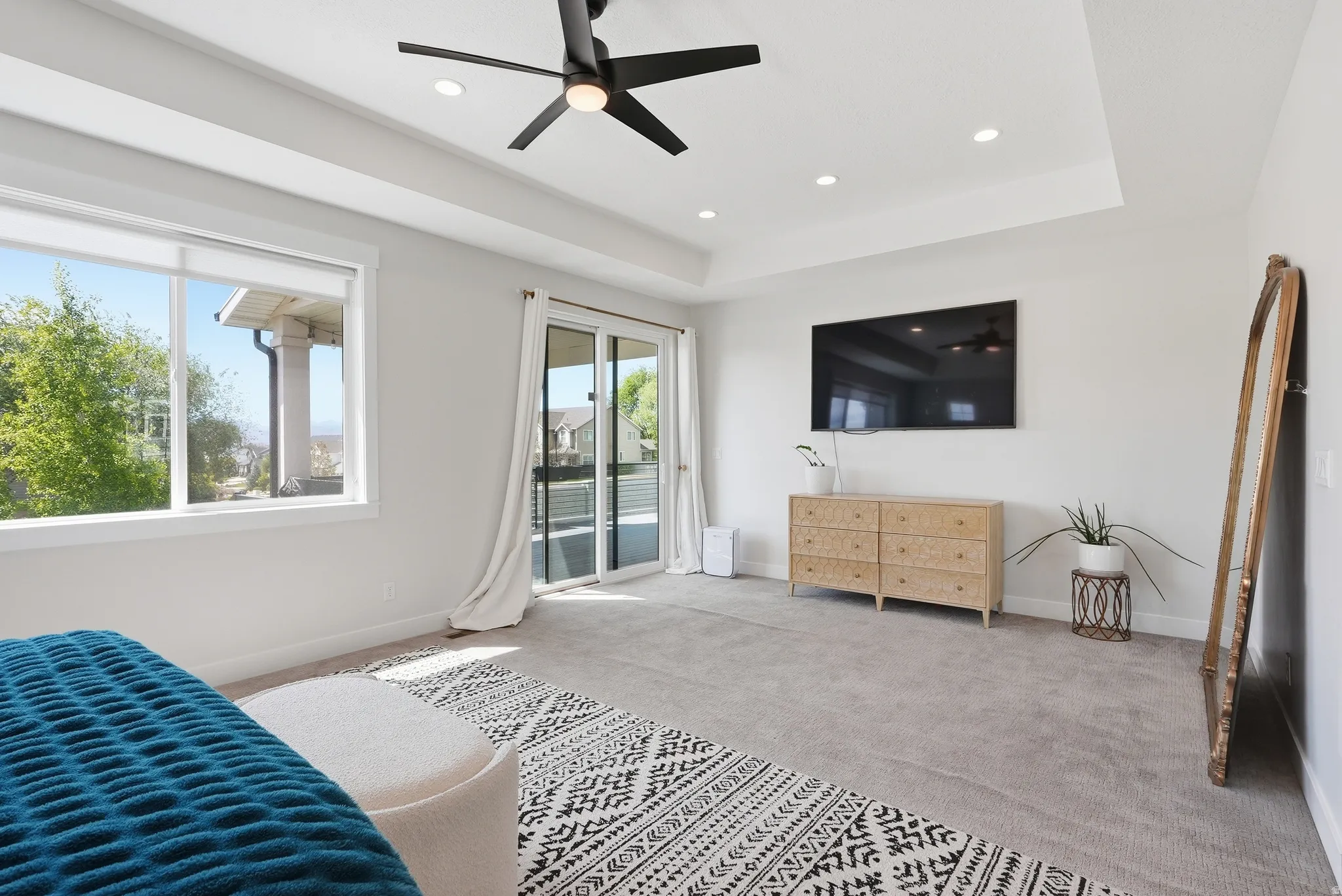 Spacious room featuring a tray ceiling with recessed lighting, a modern ceiling fan, and light-colored carpeting