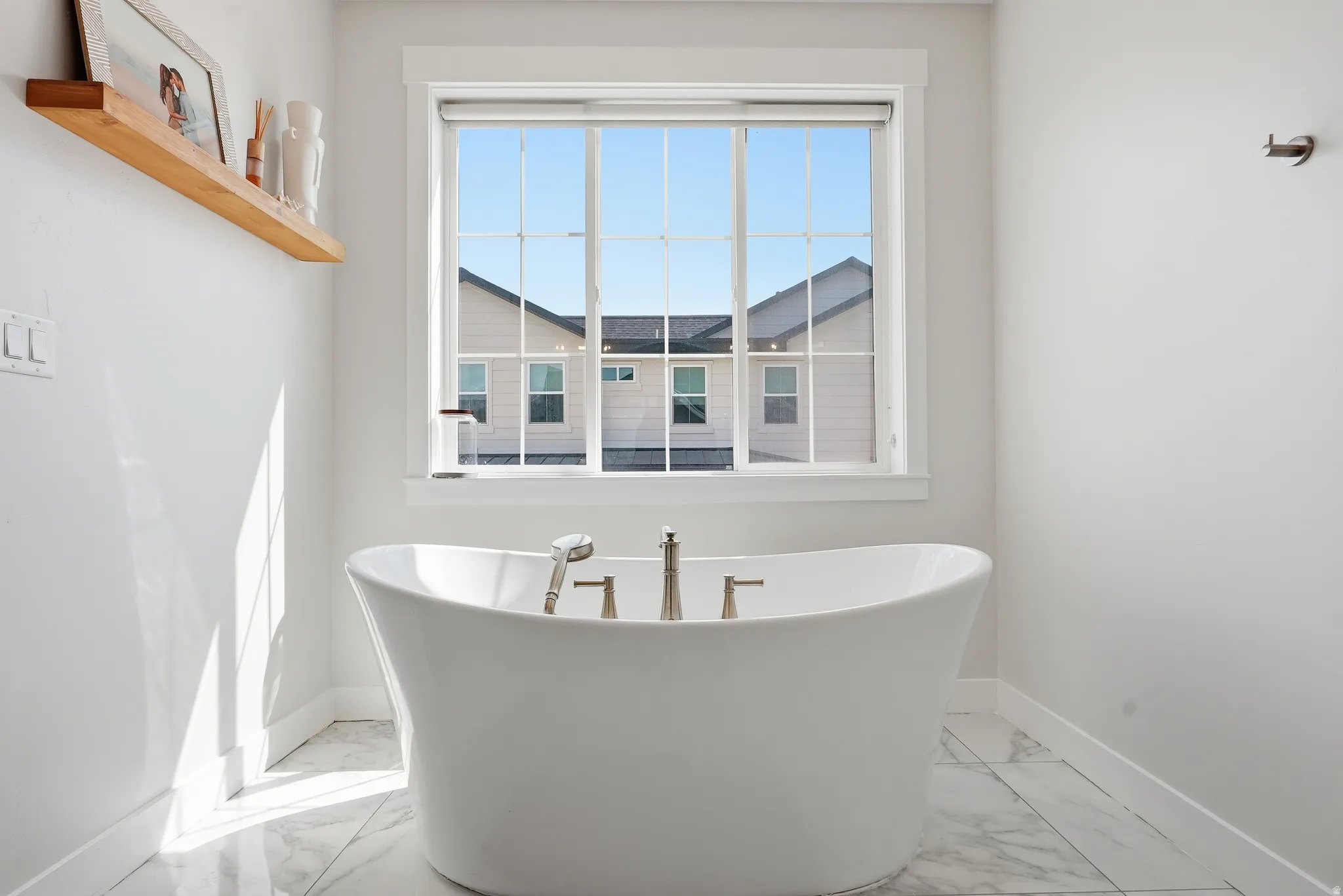 Freestanding soaking tub with polished chrome fixtures, set against a window with grid patterns
